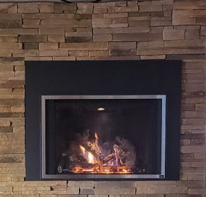 Plain black fireplace built into a brick wall